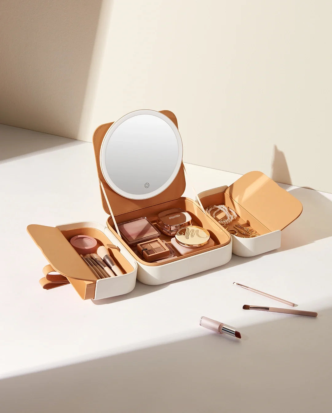 Beige makeup organizer case with round LED mirror and open storage compartments for cosmetics and makeup brushes.
