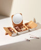 Beige makeup organizer case with round LED mirror and open storage compartments for cosmetics and makeup brushes.