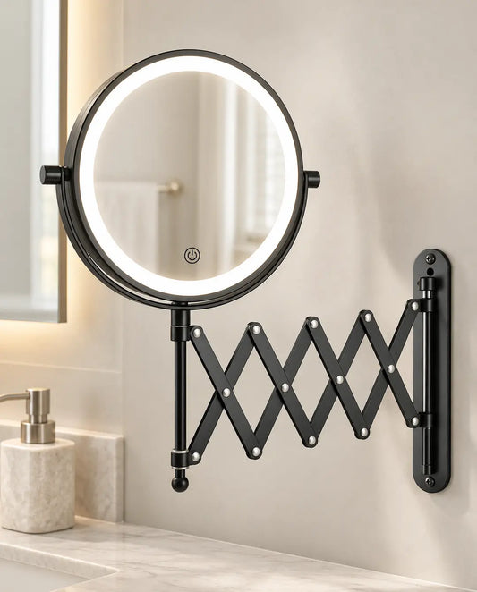Black round LED makeup mirror with an accordion-style extendable arm mounted on a bathroom wall.