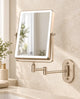 Champagne-colored rectangular LED makeup mirror with an extendable wall-mounted arm in a cream bathroom.
